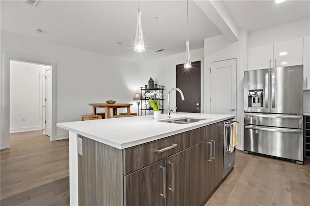 kitchen with sink, white cabinetry, light wood-type flooring, an island with sink, and appliances with stainless steel finishes