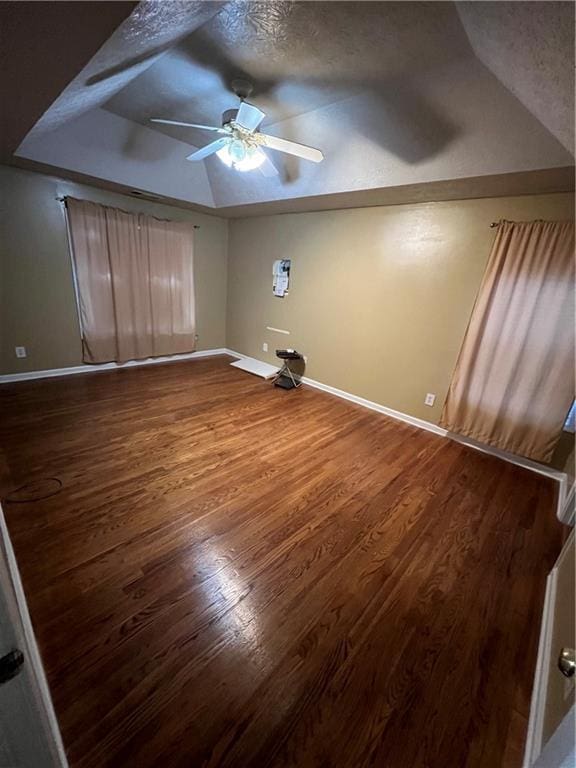 unfurnished bedroom featuring ceiling fan, a textured ceiling, wood finished floors, lofted ceiling, and baseboards