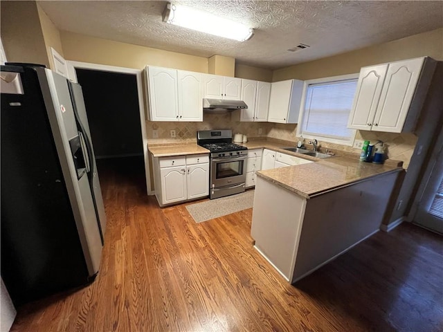 kitchen featuring visible vents, a sink, appliances with stainless steel finishes, a peninsula, and under cabinet range hood