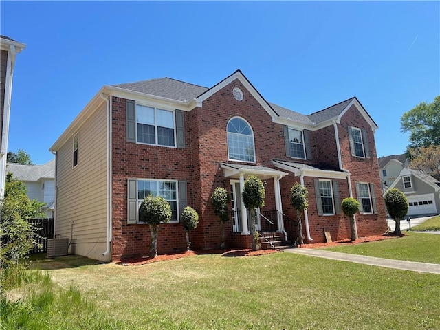 view of front of home with brick siding, a front yard, and central AC unit