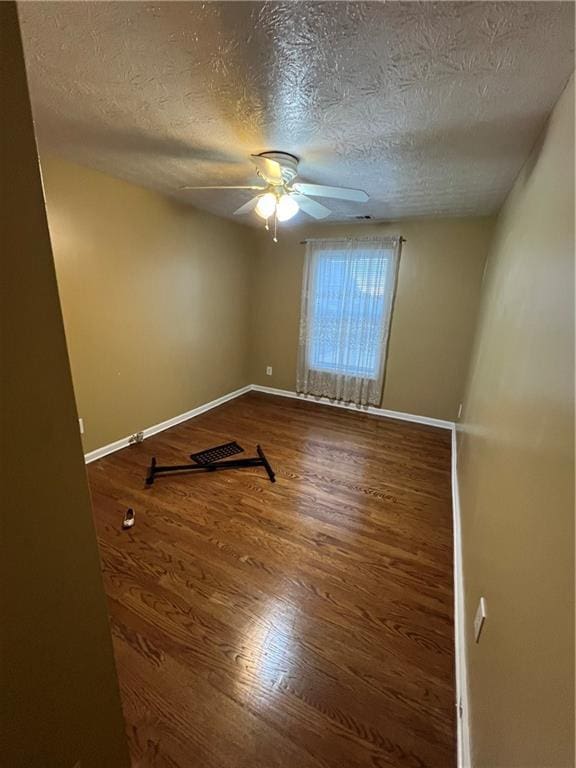 spare room with baseboards, a textured ceiling, a ceiling fan, and wood finished floors