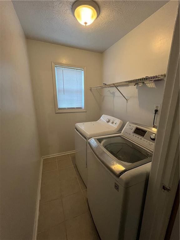 laundry room with baseboards, washing machine and dryer, a textured ceiling, light tile patterned flooring, and laundry area