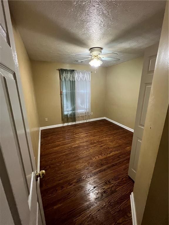 spare room featuring a textured ceiling, wood finished floors, baseboards, and a ceiling fan