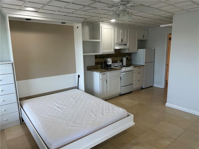 bedroom featuring baseboards, a sink, and freestanding refrigerator