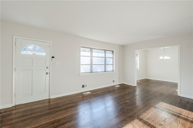 entrance foyer featuring an inviting chandelier and dark wood-type flooring