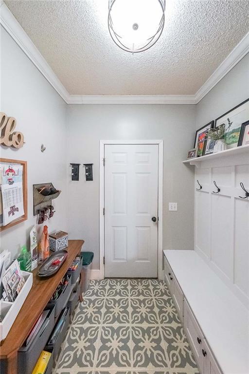 mudroom with a textured ceiling and crown molding