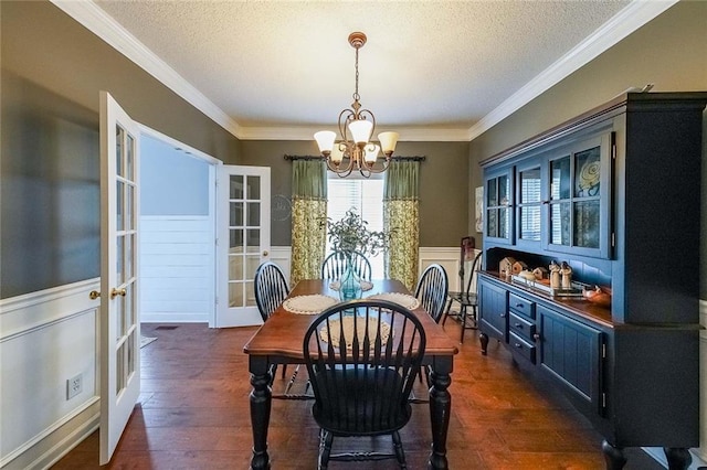 dining room with dark hardwood / wood-style floors, crown molding, a chandelier, and french doors