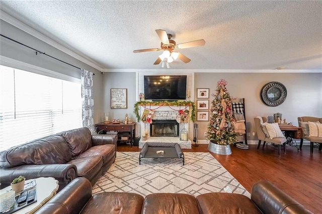 living room featuring a stone fireplace, crown molding, light hardwood / wood-style flooring, and a textured ceiling