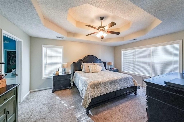 carpeted bedroom featuring ceiling fan, a textured ceiling, and a tray ceiling