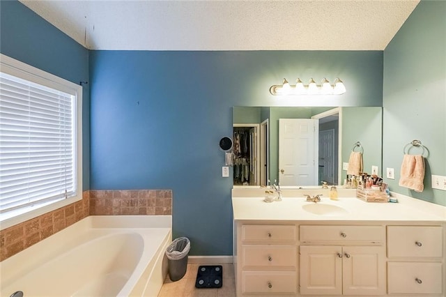 bathroom with a bathtub, vanity, a textured ceiling, and tile patterned flooring