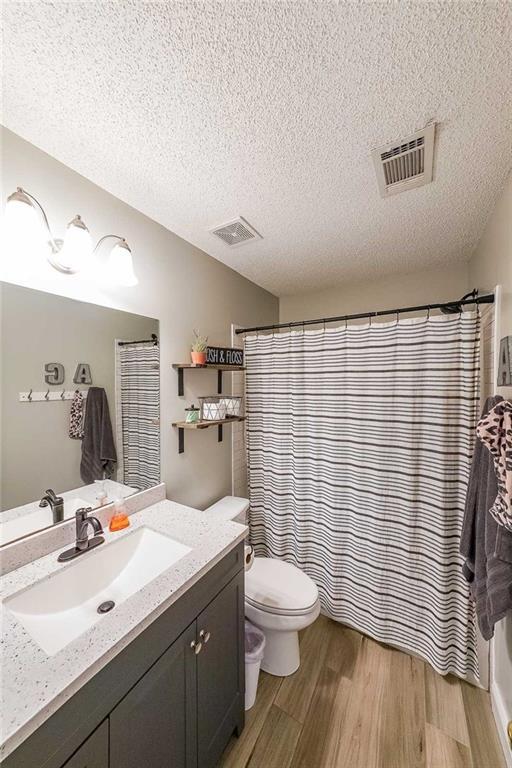 bathroom featuring hardwood / wood-style flooring, vanity, toilet, and a textured ceiling