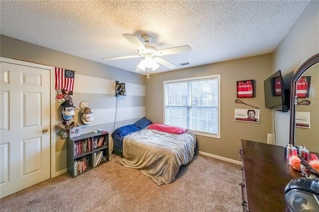 bedroom with ceiling fan, light colored carpet, and a textured ceiling