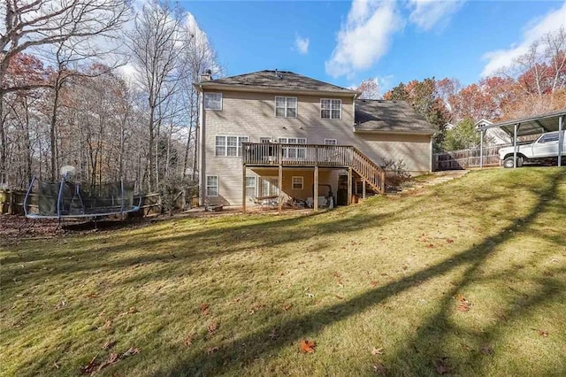 back of property with a yard, a trampoline, and a wooden deck