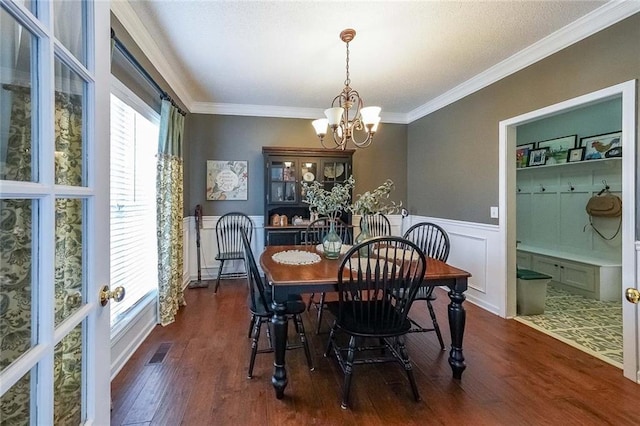 dining area with ornamental molding, dark wood-type flooring, and a notable chandelier