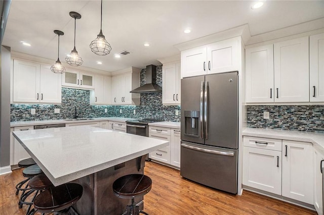 708 Mcgill Pl NE, Atlanta, GA 30312 - kitchen with appliances with stainless steel finishes, wall chimney exhaust hood, a breakfast bar area, tasteful backsplash, and recessed lighting