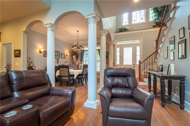 living room with wood-type flooring, a chandelier, a high ceiling, and ornamental molding