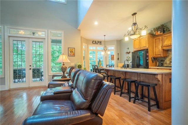 living room featuring a chandelier, french doors, light hardwood / wood-style flooring, and sink