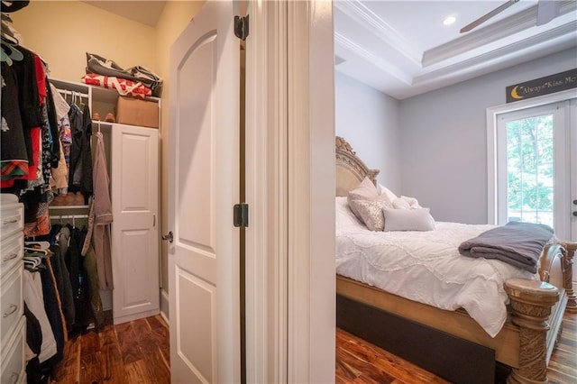 bedroom with dark hardwood / wood-style floors, a raised ceiling, crown molding, and a closet