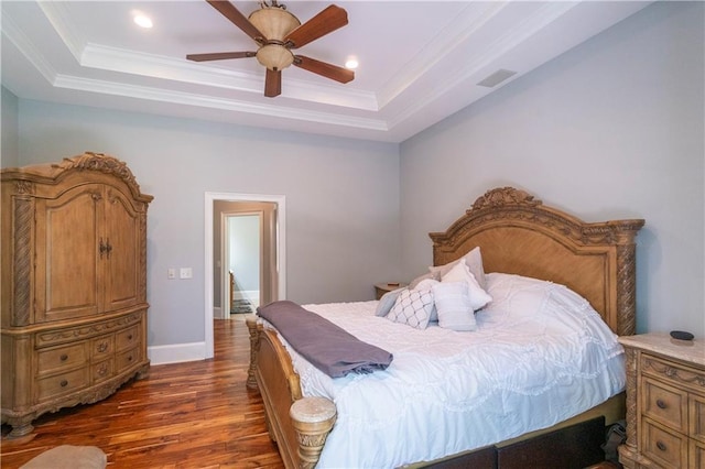 bedroom featuring a raised ceiling, ceiling fan, dark wood-type flooring, and ornamental molding