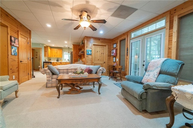 carpeted living room featuring ceiling fan and wood walls