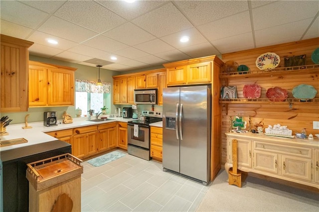 kitchen featuring appliances with stainless steel finishes, a paneled ceiling, hanging light fixtures, and sink