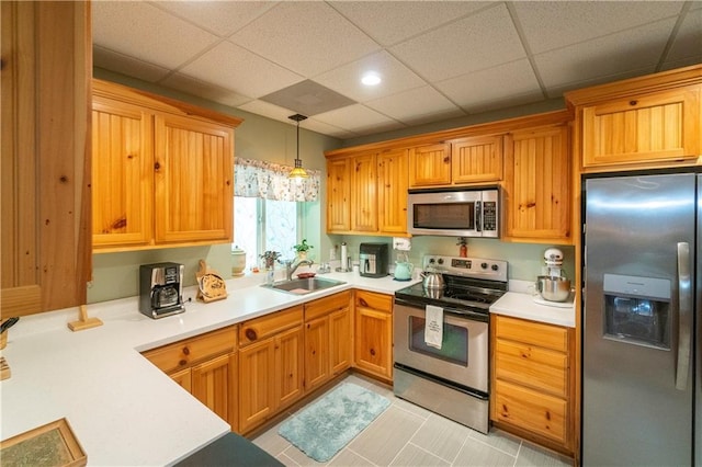 kitchen featuring a paneled ceiling, hanging light fixtures, sink, appliances with stainless steel finishes, and light tile patterned flooring