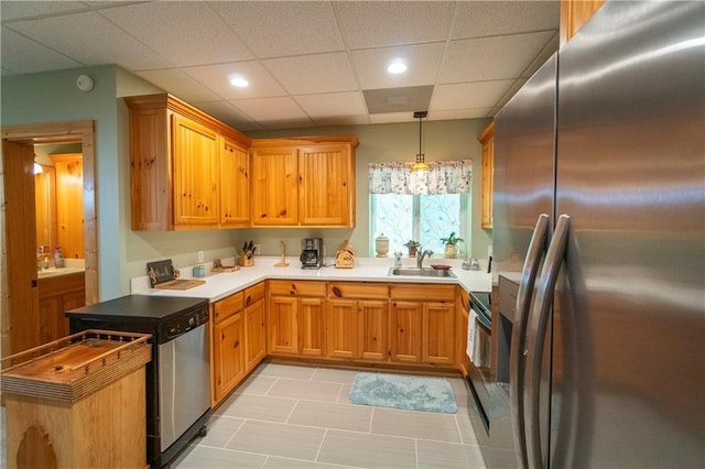 kitchen featuring pendant lighting, sink, stainless steel appliances, and a drop ceiling