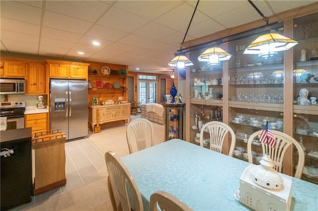 dining space featuring a drop ceiling, wood walls, and french doors