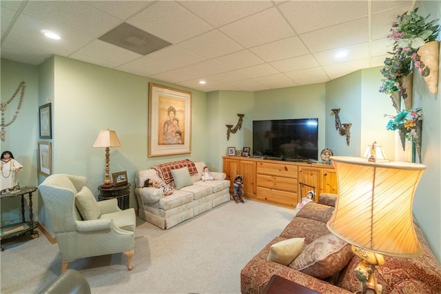 living room with a drop ceiling and carpet