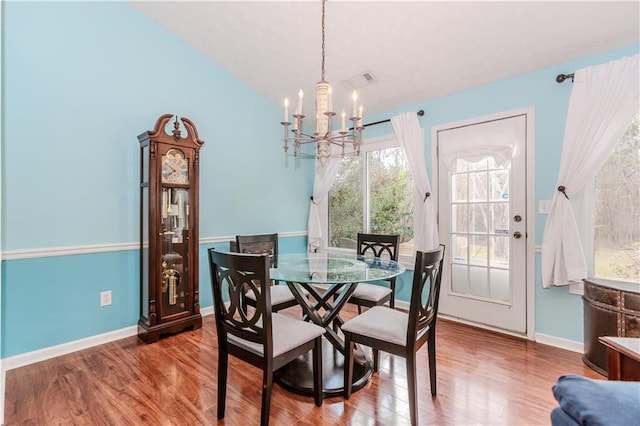 dining area featuring hardwood / wood-style flooring, lofted ceiling, and an inviting chandelier