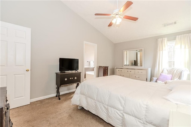 bedroom with vaulted ceiling, connected bathroom, light colored carpet, and ceiling fan