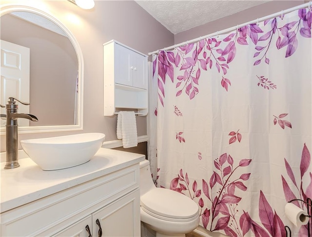 bathroom with a shower with curtain, vanity, toilet, and a textured ceiling