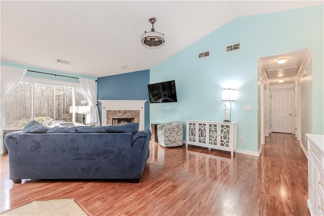 living room with lofted ceiling, hardwood / wood-style flooring, and a fireplace