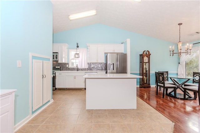 kitchen with white cabinetry, hanging light fixtures, stainless steel appliances, and sink