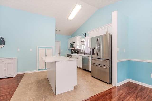 kitchen with pendant lighting, sink, appliances with stainless steel finishes, white cabinets, and a kitchen island