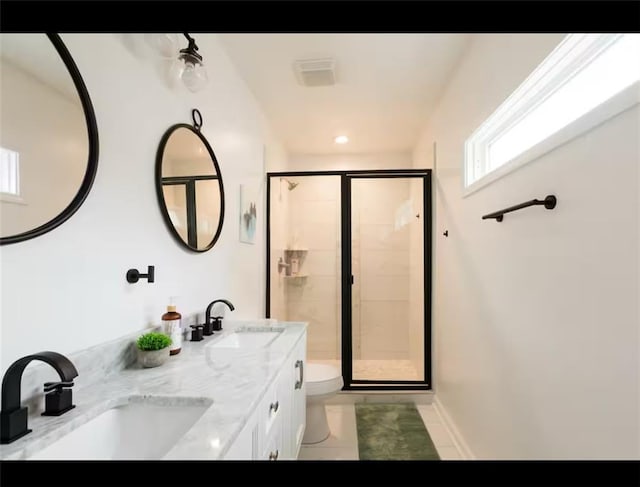 bathroom with a shower with door, vanity, toilet, and tile patterned floors