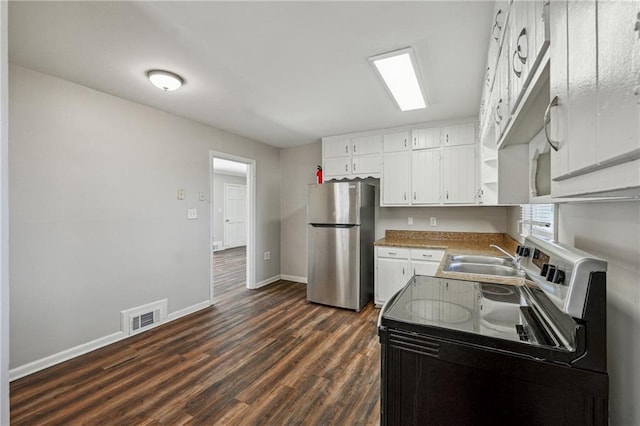 kitchen featuring visible vents, range with electric cooktop, a sink, freestanding refrigerator, and white cabinetry