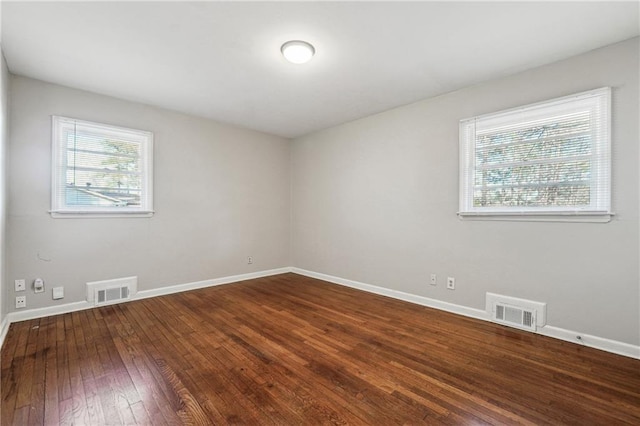 unfurnished room featuring visible vents, baseboards, and hardwood / wood-style floors