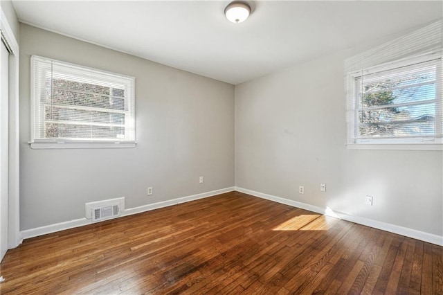 unfurnished room featuring visible vents, baseboards, and wood-type flooring