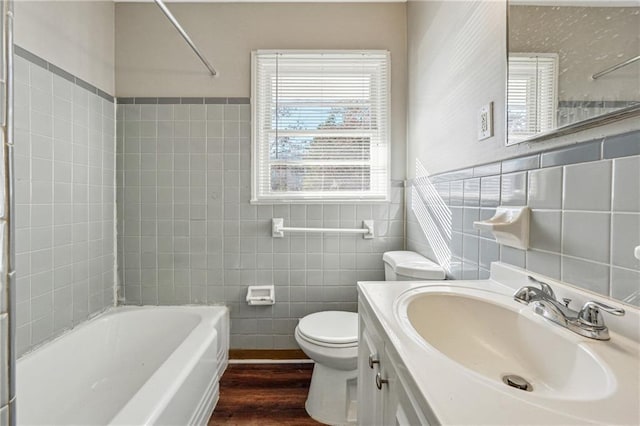 bathroom with tile walls, toilet, bathtub / shower combination, vanity, and wood finished floors