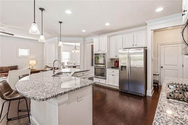 kitchen with hanging light fixtures, sink, a kitchen island with sink, white cabinetry, and appliances with stainless steel finishes