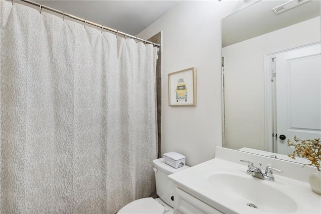 bathroom with walk in shower, vanity, and toilet