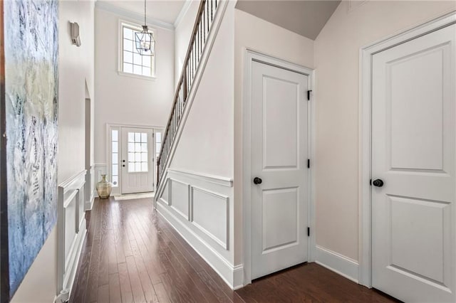 foyer entrance with ornamental molding, an inviting chandelier, dark wood-type flooring, and plenty of natural light