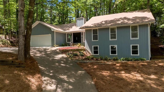 view of front of home featuring a garage, a chimney, and driveway