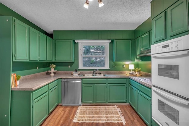 kitchen with a sink, light wood-style floors, white appliances, light countertops, and a textured ceiling