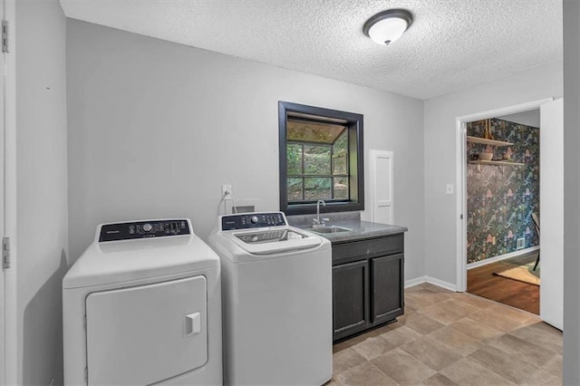 clothes washing area featuring washing machine and dryer, baseboards, a textured ceiling, a sink, and cabinet space