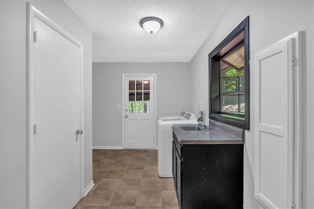 clothes washing area featuring laundry area, a textured ceiling, a sink, baseboards, and separate washer and dryer