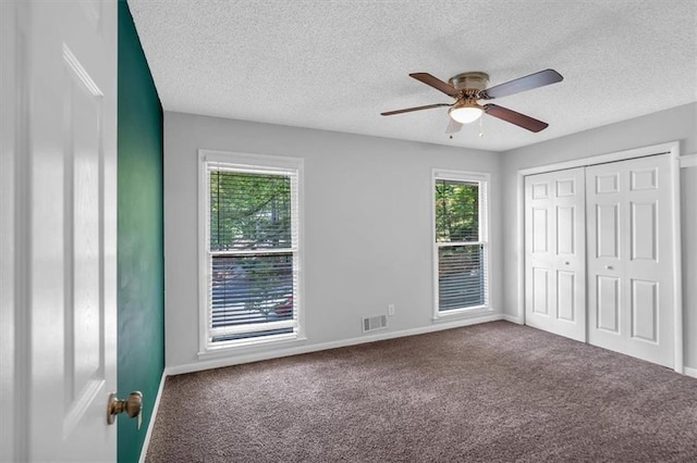unfurnished bedroom with visible vents, a textured ceiling, and multiple windows