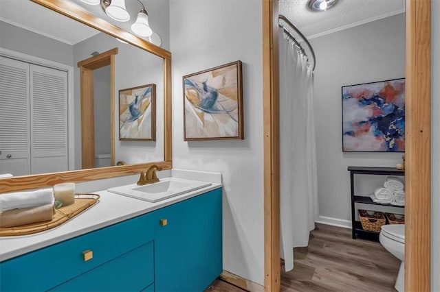 full bath featuring crown molding, vanity, toilet, a textured ceiling, and wood finished floors