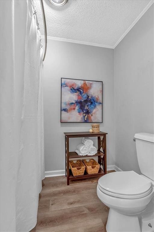 bathroom featuring a textured ceiling, ornamental molding, toilet, and wood finished floors